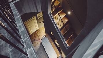 A multi-level interior with a staircase, a stone floor, and a view of a kitchen area.