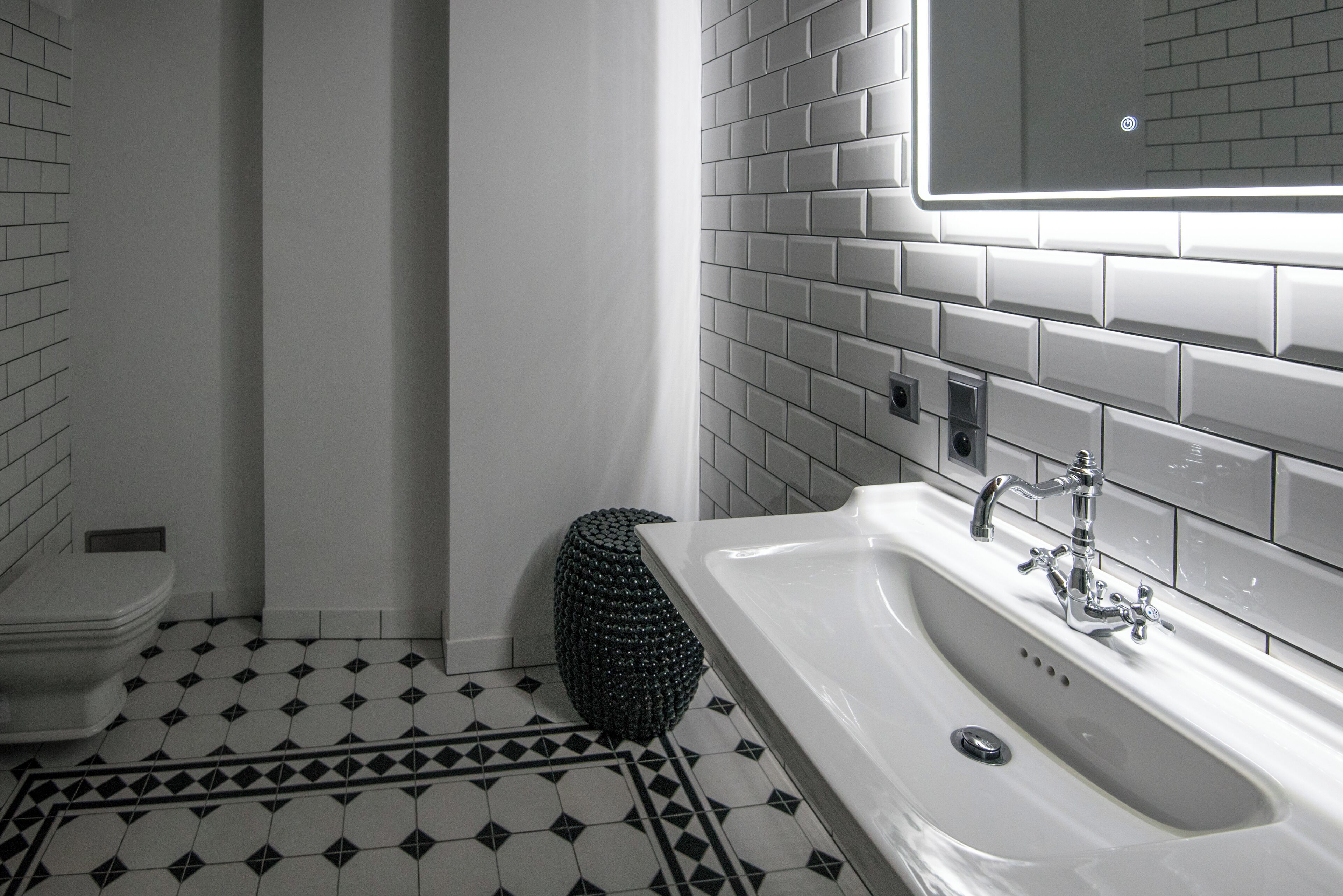 Een badkamer met een wit wastafelmeubel, een toilet en een vloer met een patroon.