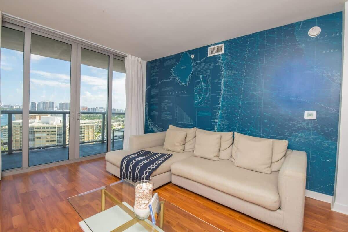 A living room with a large window, a sofa, a coffee table, and a wall map.