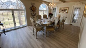 A dining room with a large table set for six, surrounded by ornate chairs, large windows, and a chandelier. - Toad Hall Manor  (Butte)