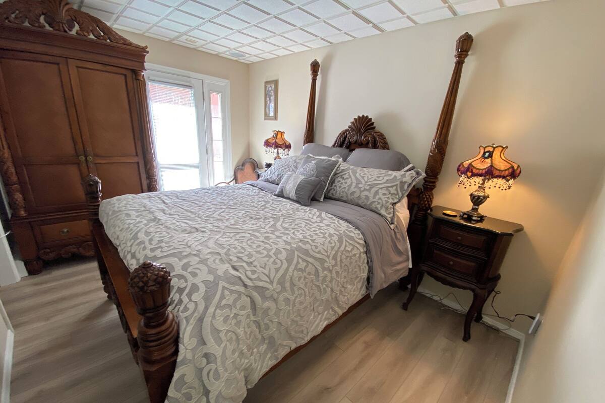 A bedroom with a four-poster bed, wooden nightstands, and a chandelier.