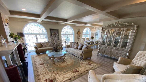 A spacious living room with a large chandelier, elegant furniture, and a grand piano. - Toad Hall Manor  (Butte)