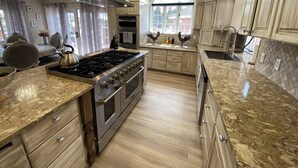 A modern kitchen with a large stove, oven, and a window providing natural light. - Toad Hall Manor  (Butte)