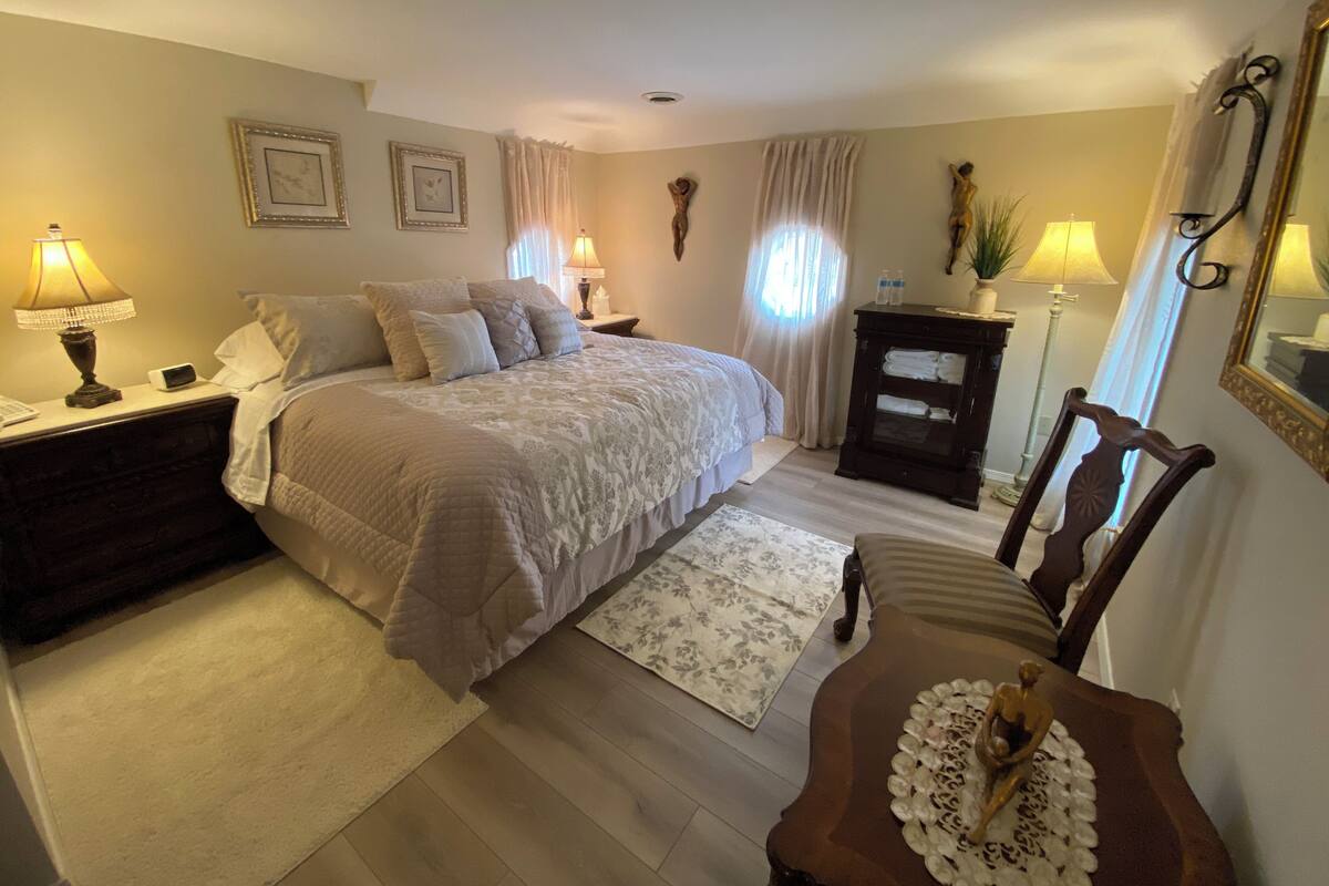 A bedroom with a bed, nightstands, a dresser, a chair, and a mirror.