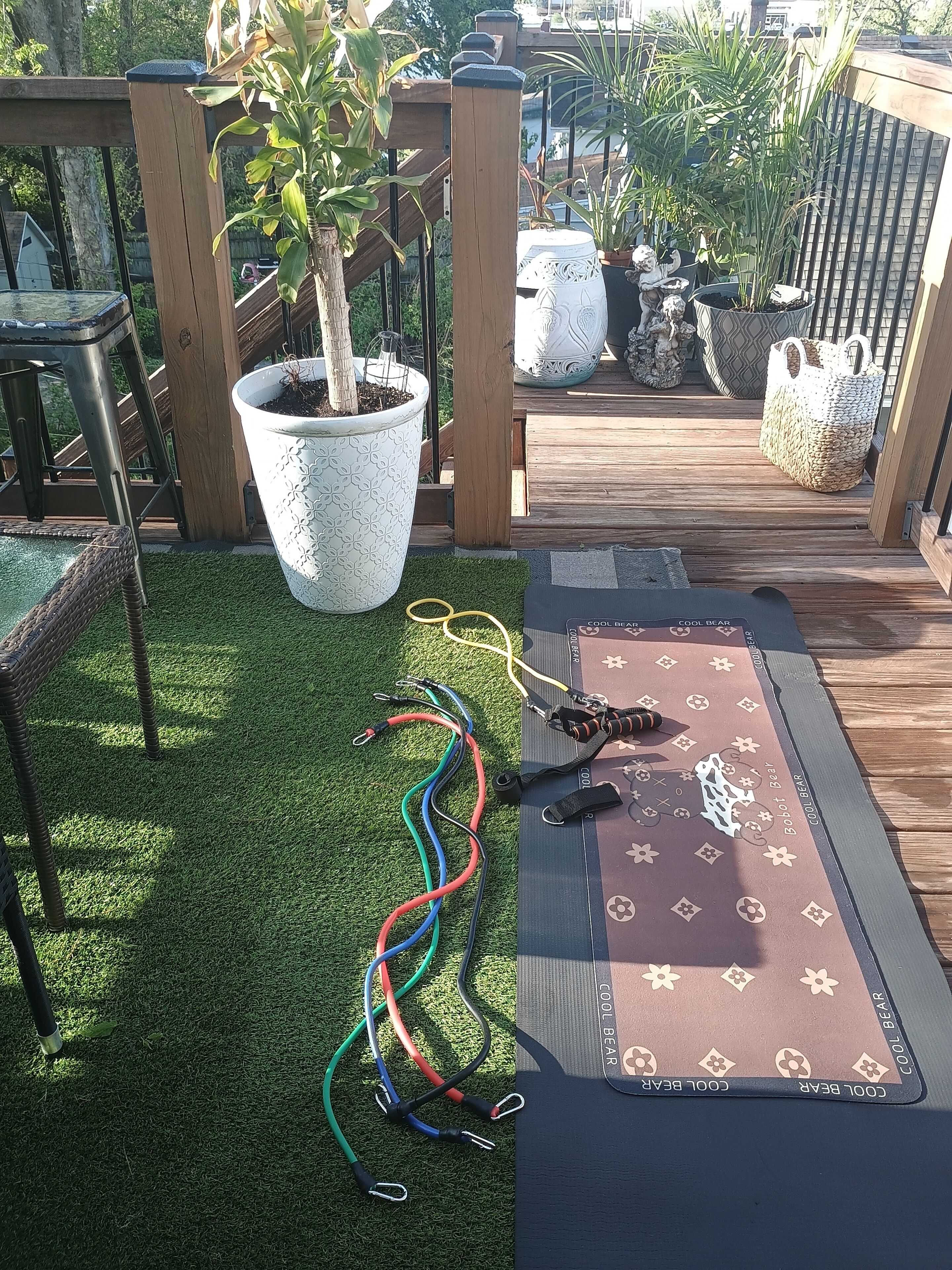 A deck with artificial grass, a yoga mat, and exercise equipment.