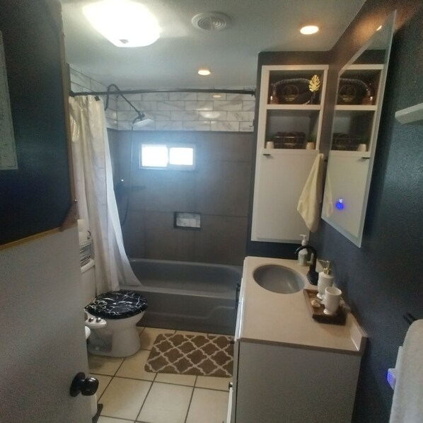 A bathroom with a bathtub, toilet, sink, and a mirror.
