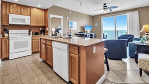 A modern kitchen with built-in appliances, a dining area with a view, and a balcony with a ceiling fan.