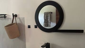 A bathroom with a white sink, black faucet, and a round mirror with a black frame.