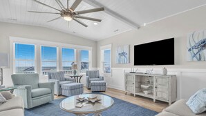 A spacious living room with a large TV, comfortable seating, and a view of the city. - Vitamin Sea: Coastal Chic Home with Private Pool, Elevator (Oak Island)