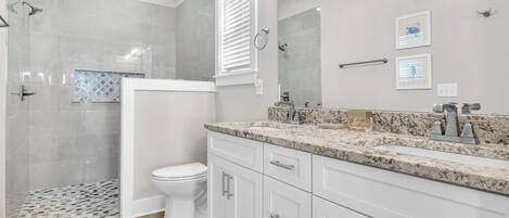 A modern bathroom with a shower, toilet, and vanity with a sink.