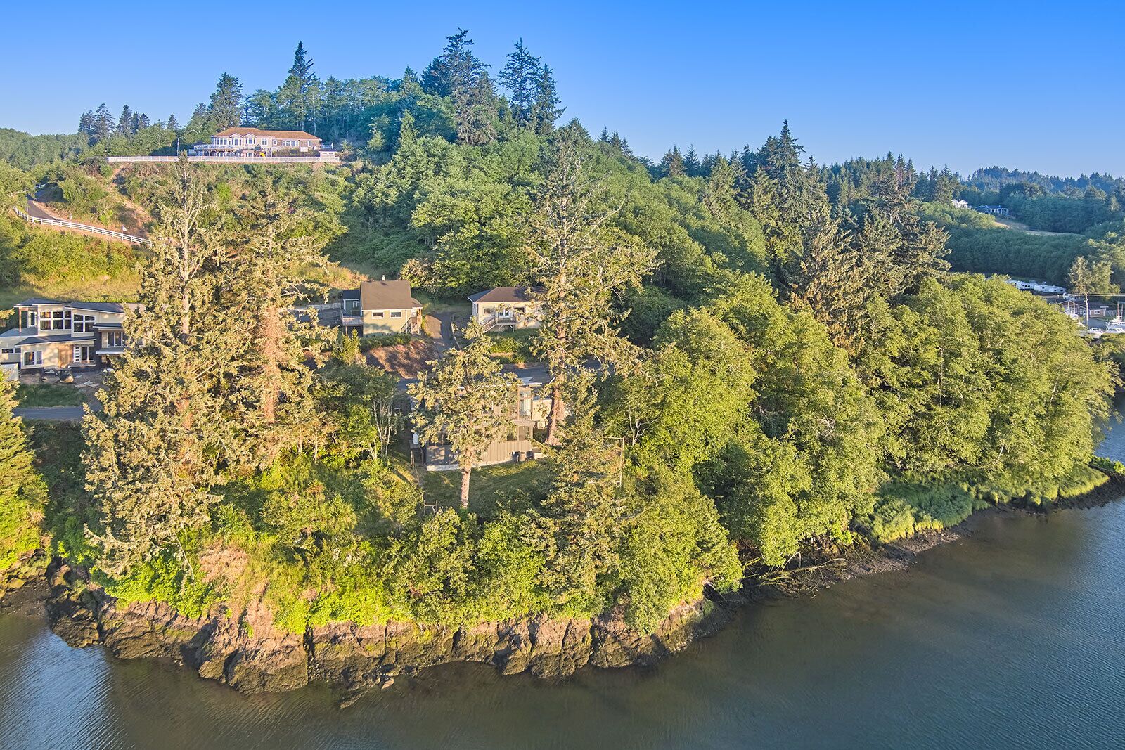 A coastal property with multiple houses surrounded by dense forest, overlooking a body of water.