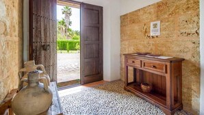 A room with a rustic wooden door, a stone wall, a wooden cabinet, and a patterned floor. - Villa Roig, Stone villa in the country (Pollença)