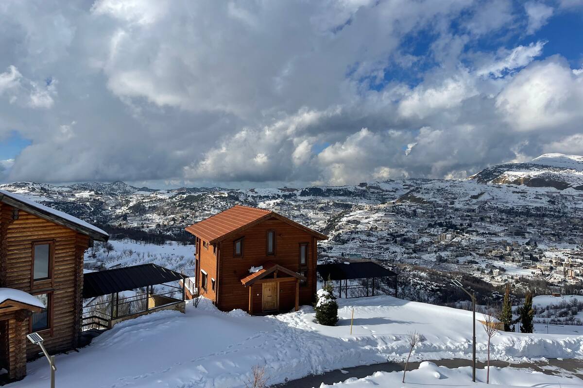 A wooden cabin with a snow-covered landscape in the background.