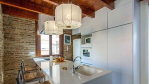 Een moderne keuken met een centraal kookeiland, witte kastjes en een achterwand van bakstenen.