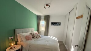 Une chambre à coucher avec un lit, une table de chevet avec une lampe, une fenêtre avec des rideaux et une porte.