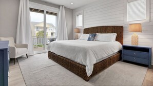Ein Schlafzimmer mit einem großen Bett, einem Nachttisch, einem Sessel und Blick ins Freie.