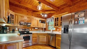 A wooden cabin-style kitchen with a stainless steel refrigerator, oven, and dishwasher.