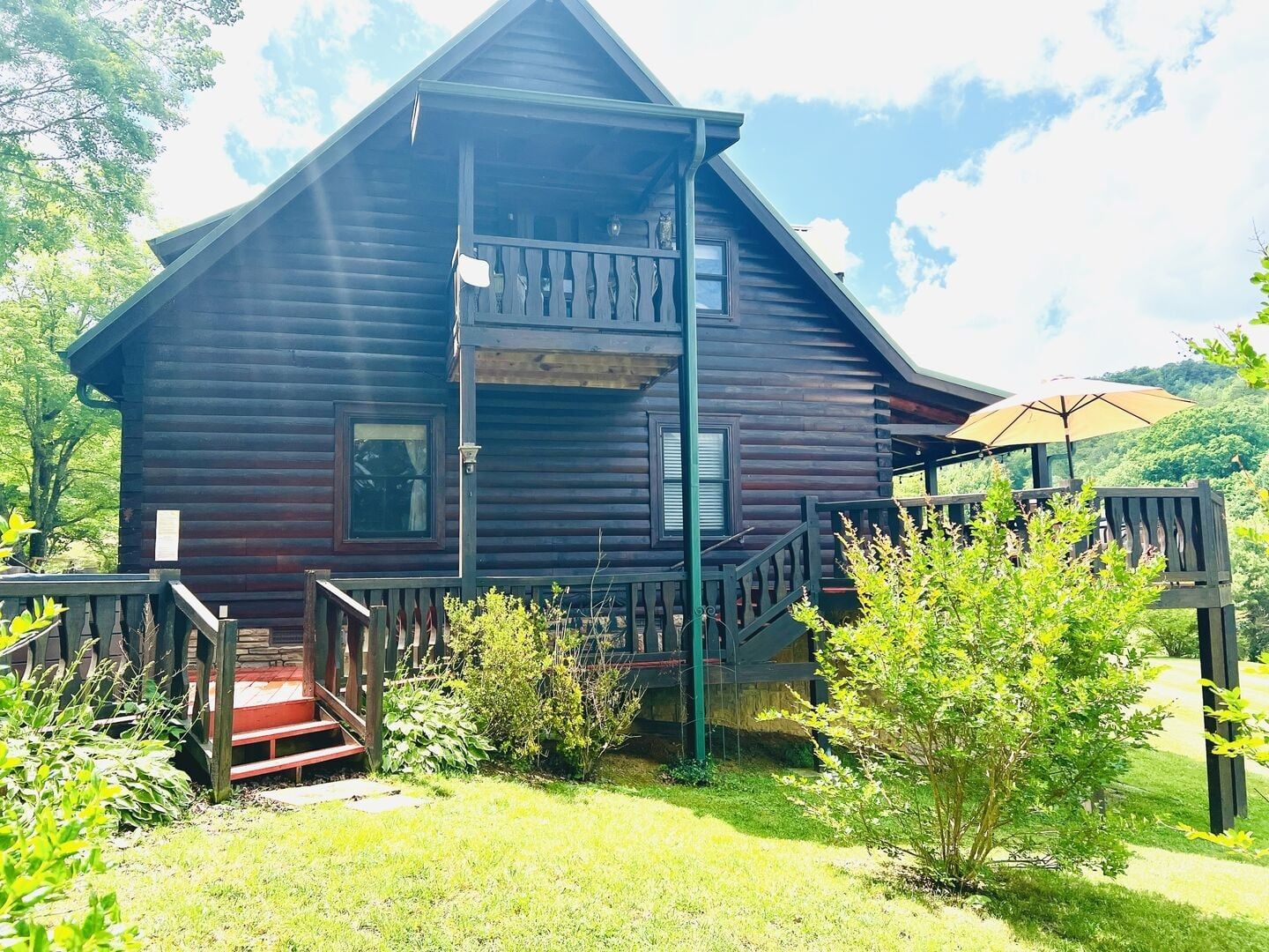 A wooden cabin with a balcony, a staircase, and a small porch area.