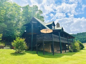 A wooden cabin with a balcony and a covered porch area.