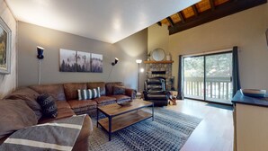 Amplia sala de estar con sofá de cuero, mesa de centro de madera y chimenea.