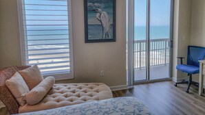 A bedroom with a large window, a painting of a bird, a bed, and a chair.
