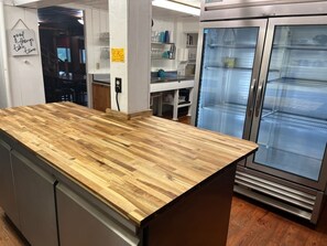 A kitchen with a wooden countertop, stainless steel appliances, and a refrigerator. - Little Greenbriar Lodge 13 Bedroom Cabin by RedAwning (Sevierville)