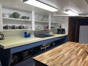 A kitchen with a wooden countertop, a sink, and various kitchen utensils and appliances. - Little Greenbriar Lodge 13 Bedroom Cabin by RedAwning (Sevierville)