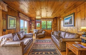 A wooden interior with leather sofas, a rug, and framed pictures. - Little Greenbriar Lodge 13 Bedroom Cabin by RedAwning (Sevierville)