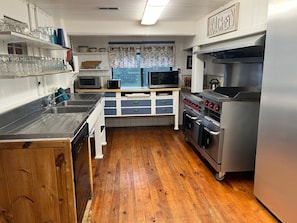 A kitchen with a wooden floor, stainless steel appliances, and a 'Kitchen' sign. - Little Greenbriar Lodge 13 Bedroom Cabin by RedAwning (Sevierville)