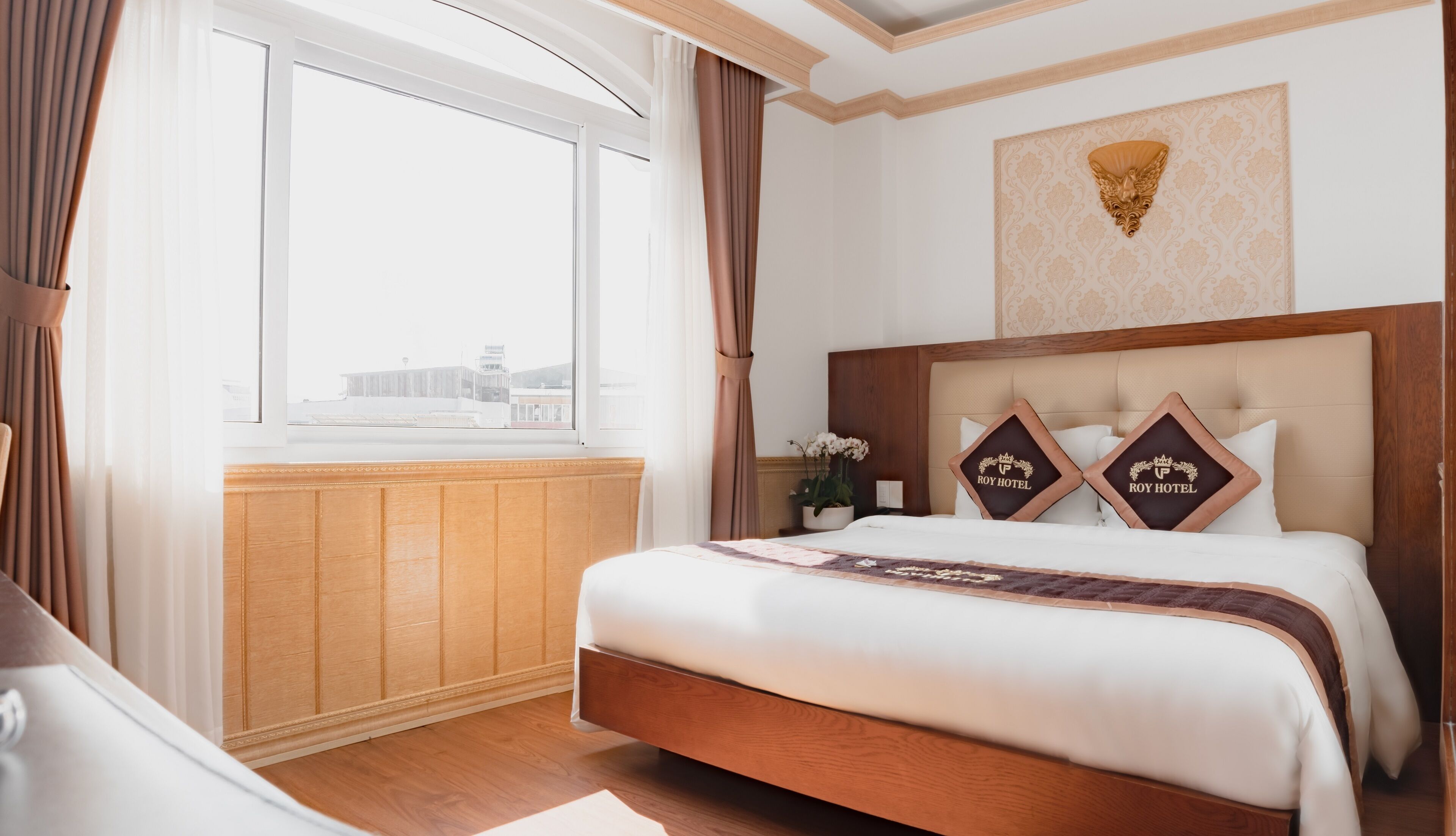 Una habitación de hotel con una cama grande, cabecero de madera y una ventana con cortinas.