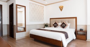 Ein Hotelzimmer mit einem großen Bett, einem Nachttisch, einem Spiegel und einer Wanddekoration.