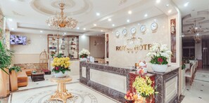 A hotel reception area with a marble counter, a chandelier, and clocks indicating different time zones. - ROY Dala Hotel (Xuan Huong - Da Lat)