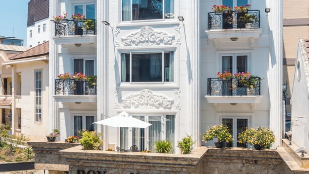 Un hotel blanco con balcones, una entrada central y un cartel que dice "ROYAL HOTEL".