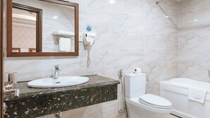 Un baño con lavamanos de mármol, inodoro y bañera.
