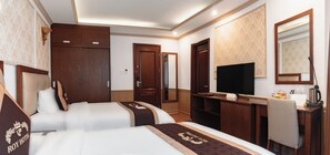A hotel room with two beds, a television, a desk with a coffee maker, and a mirror. - ROY Dala Hotel (Xuan Huong - Da Lat)