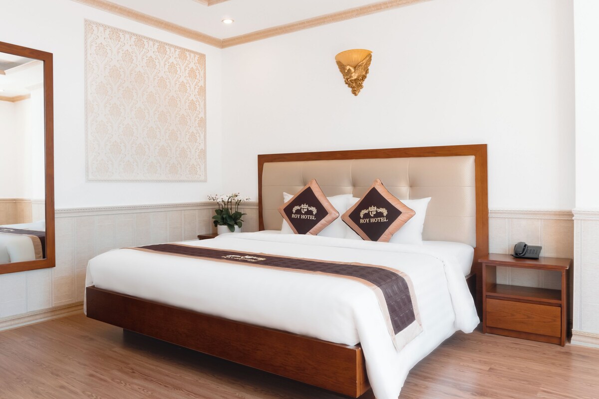 Habitación de hotel con una cama grande, una mesita de noche, una lámpara fijada a la pared y un espejo.