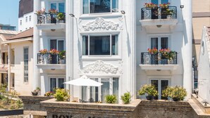 Et hvidt hotel med altaner, en central indgang og et skilt, der siger "ROYAL HOTEL".