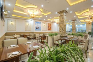 Een restaurant met meerdere eettafels, stoelen en diverse kunstwerken aan de muur.