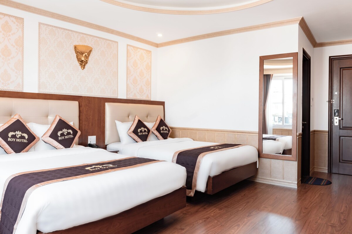 Habitación de hotel con dos camas, cabecera de madera, lámpara de pared y espejo.
