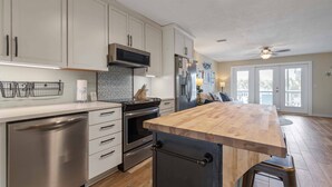 A modern kitchen with stainless steel appliances, a wooden island, and a view to the outside. - Narvana-Gulf View Home Across from Beach. Pup Friendly (Navarre)