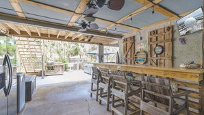 A rustic outdoor seating area with wooden benches and a bar counter. - Narvana-Gulf View Home Across from Beach. Pup Friendly (Navarre)
