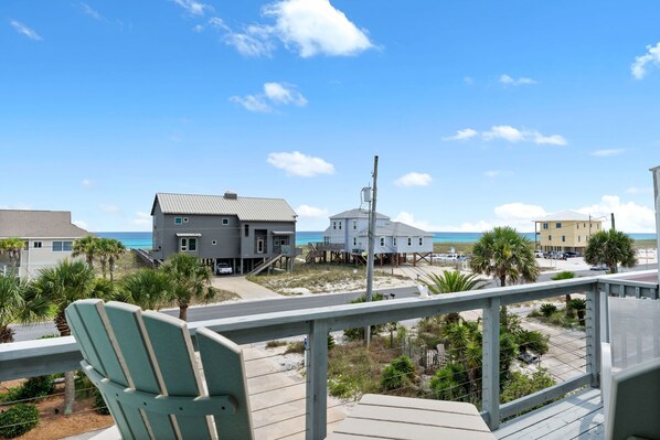 A beachfront property with a wooden deck, a chair, and a view of the ocean.