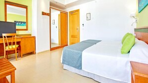 A bedroom with a bed, a desk, and a chair. There is a door leading to another room. - Universal Hotel Laguna (Capdepera)