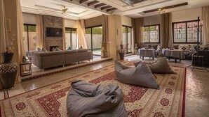 A spacious living room with a sofa, bean bags, a TV, and a fireplace. - Magnifique Villa Azao, Jusqu'à 6 Chambres /pool/jacuzzi (Marrakech)