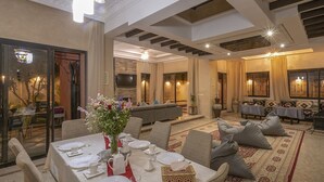 A dining area with a table set for four, a sofa, and a patterned rug. - Magnifique Villa Azao, Jusqu'à 6 Chambres /pool/jacuzzi (Marrakech)