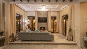 A modern living room with a sofa, a fireplace, and a television. - Magnifique Villa Azao, Jusqu'à 6 Chambres /pool/jacuzzi (Marrakech)