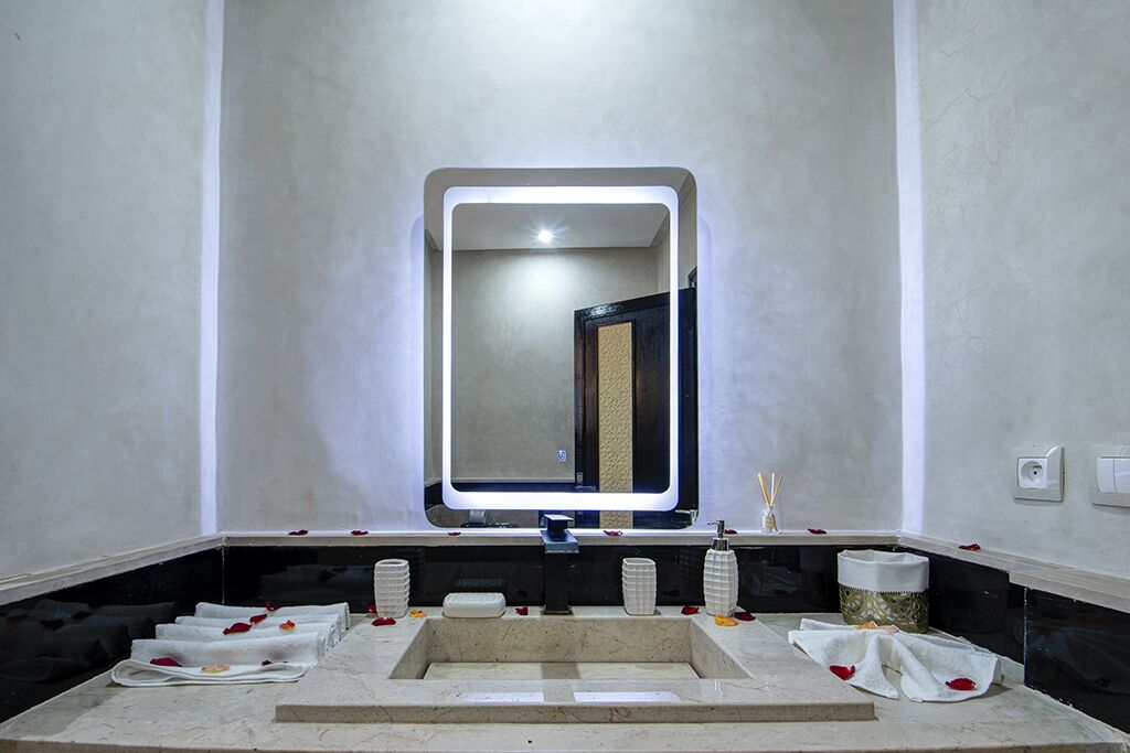A modern bathroom with a large mirror, a sink, and a vanity area.