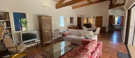 A spacious living room with a high ceiling, a large sofa, a television, and a cabinet.