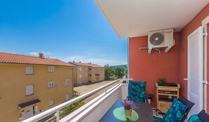 Ein Balkon mit Tisch, Stühlen und einer Topfpflanze.
