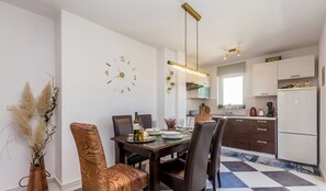 Eine moderne Küche mit weißen Schränken, einem schwarz-weißen Schachbrettfußboden und einem Essbereich mit einem Holztisch und Stühlen.